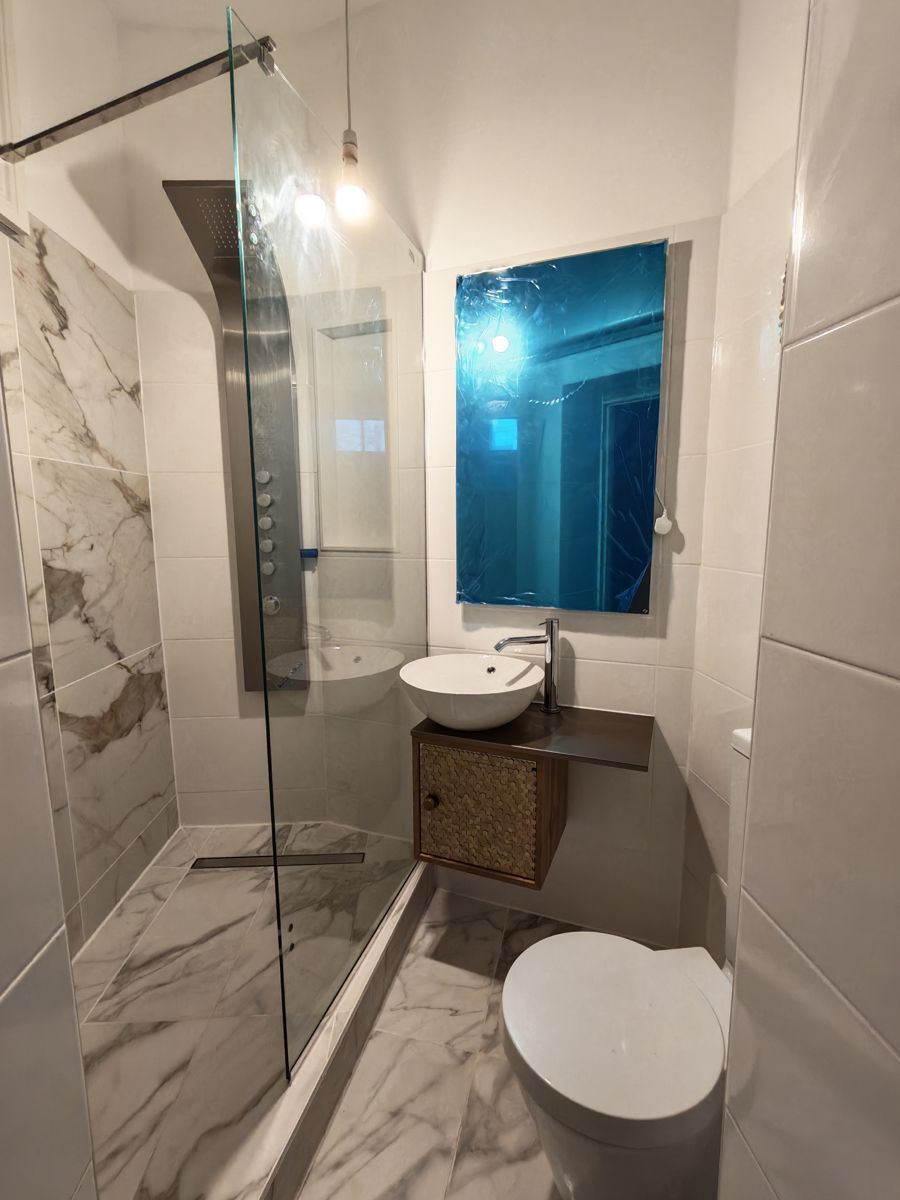 Bathroom with marble-effect tiles, glass shower screen and a floating vanity with a round basin