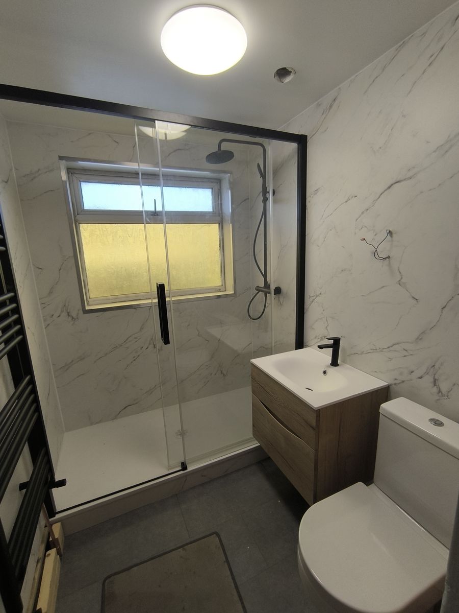 Finished bathroom with a walk-in shower, glass screen, wall-hung vanity unit and toilet