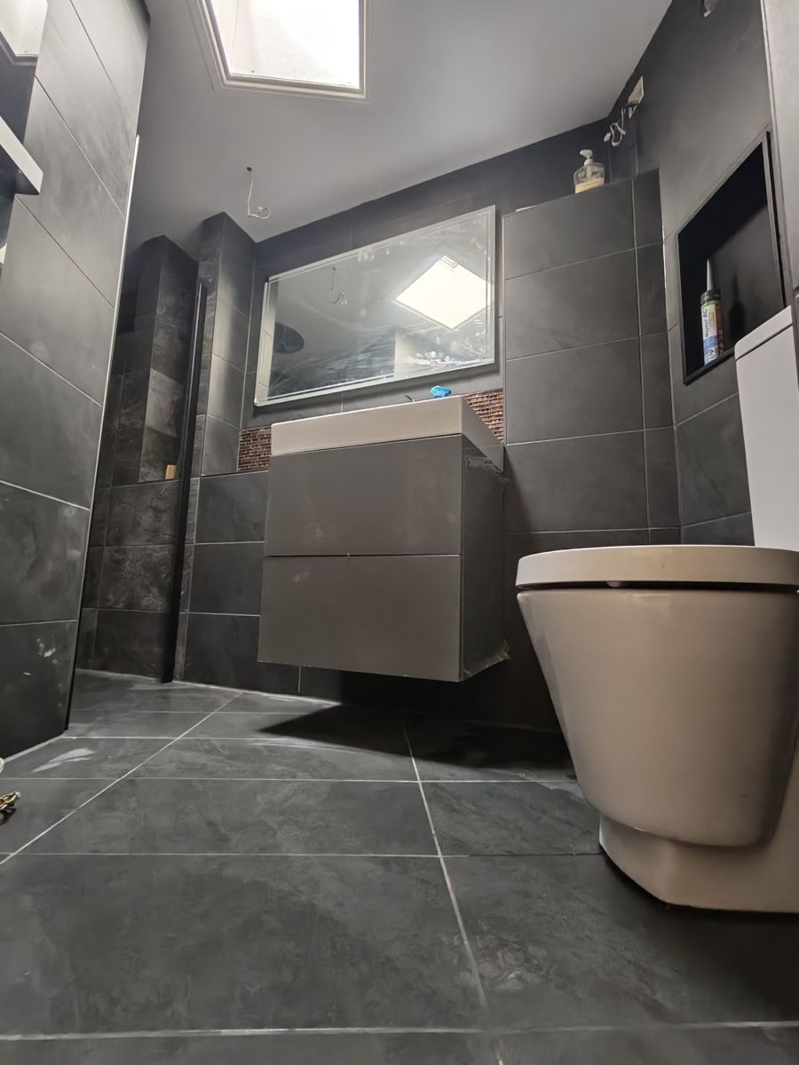Finished bathroom with large dark grey tiles, a wall-hung vanity unit and a wall-hung toilet